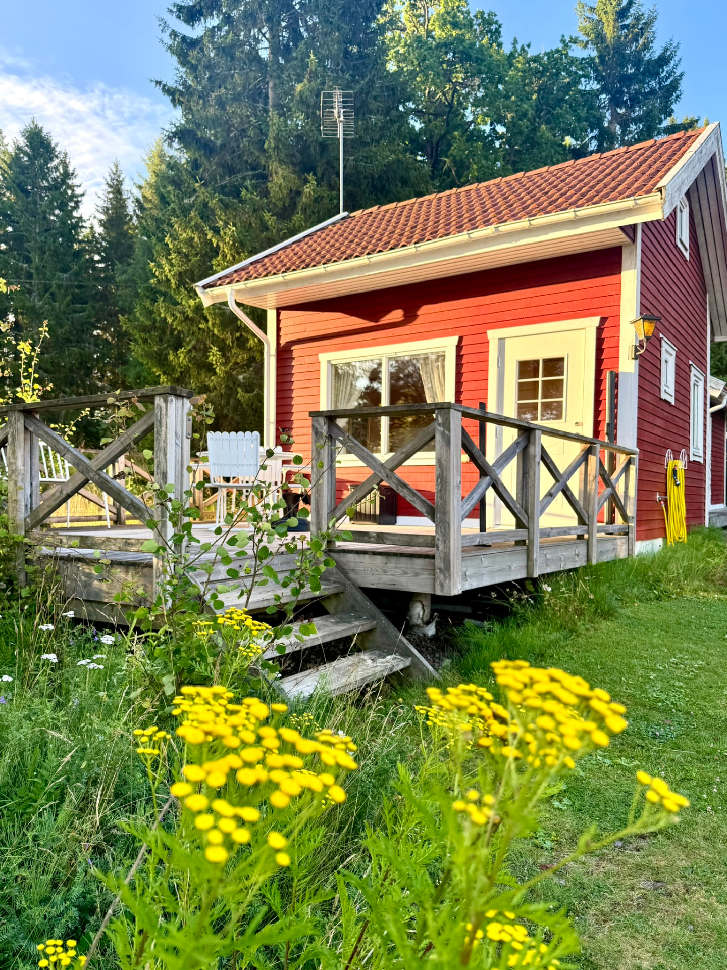 The red cottage with its wooden terrace and summer flowers