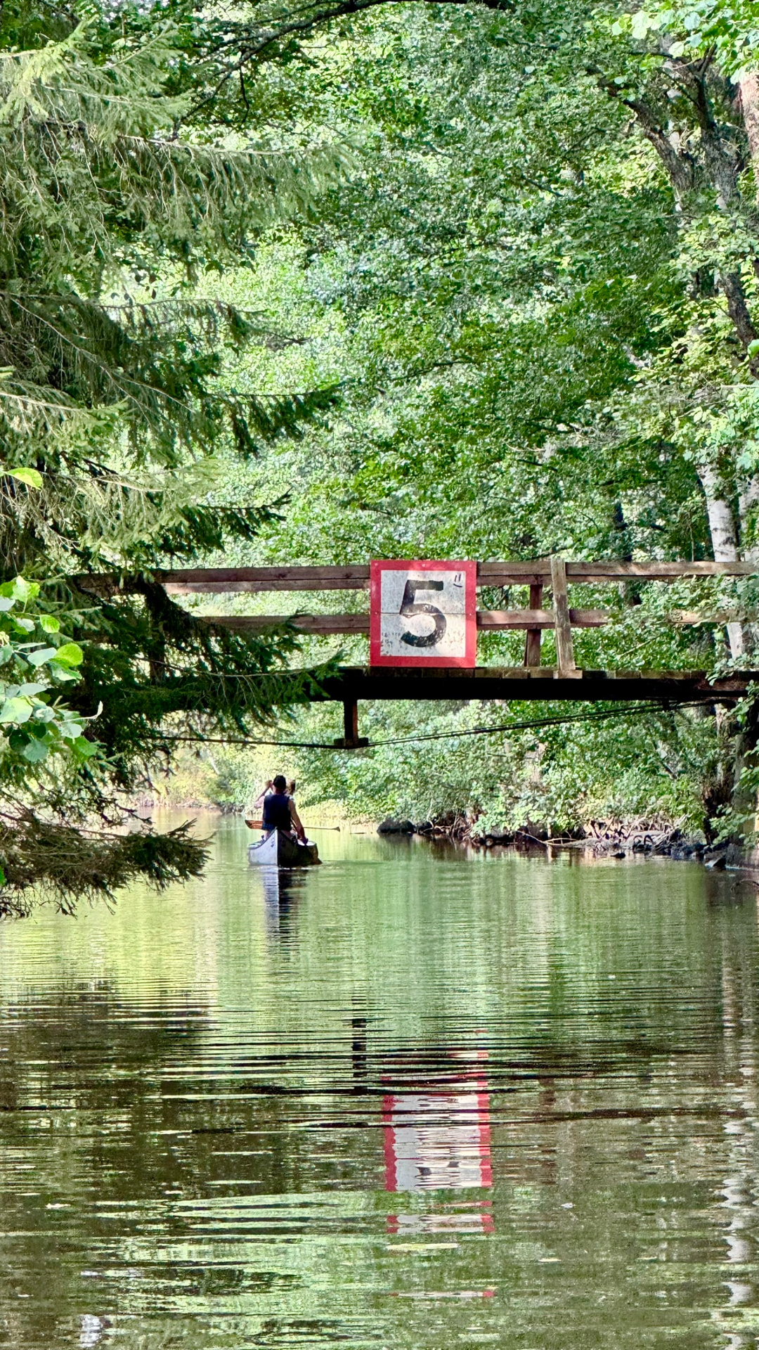 A canoe passing under a small bridge on the narrow canal
