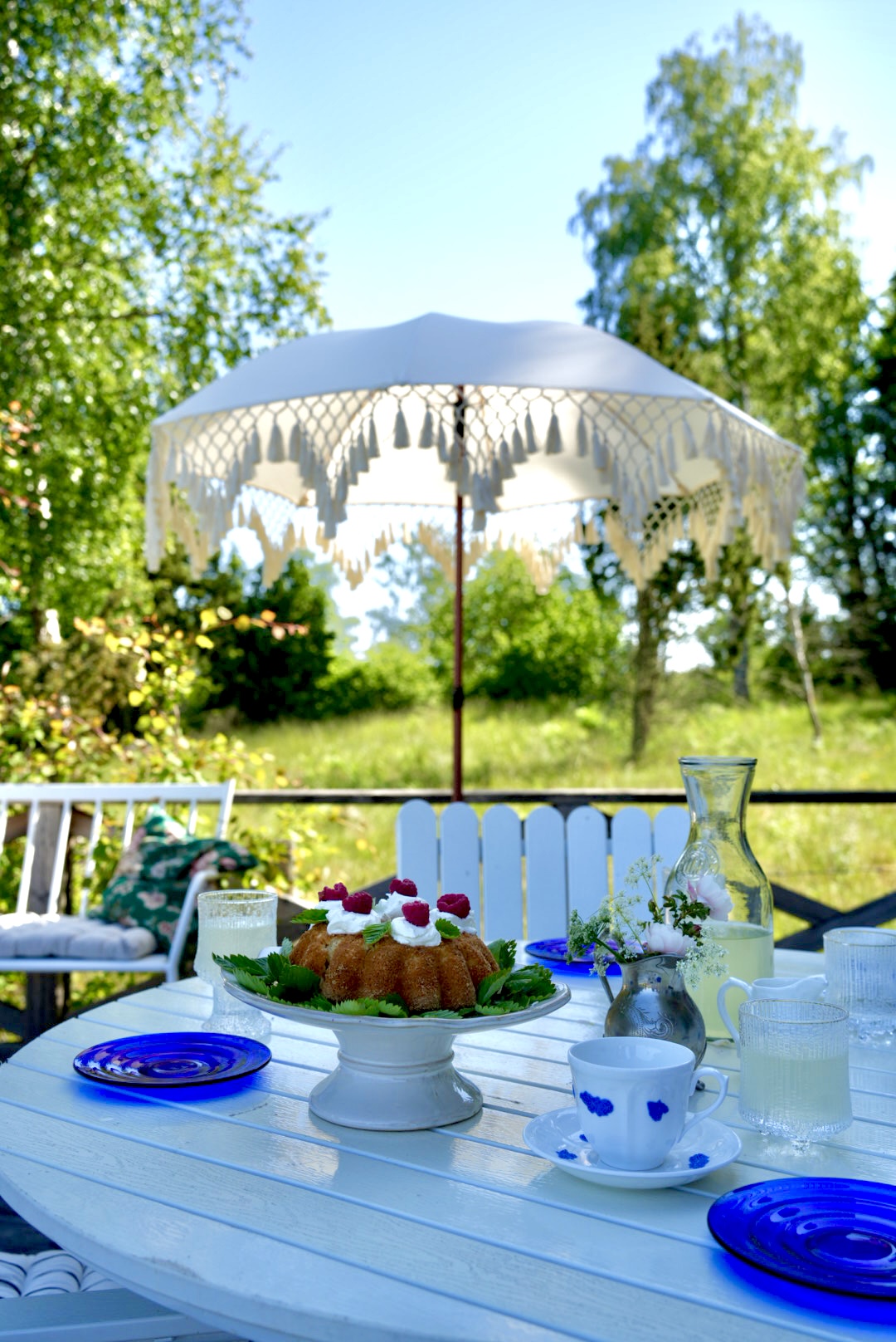 Table set with cake and lemonade under the tasselled parasol on the terrace