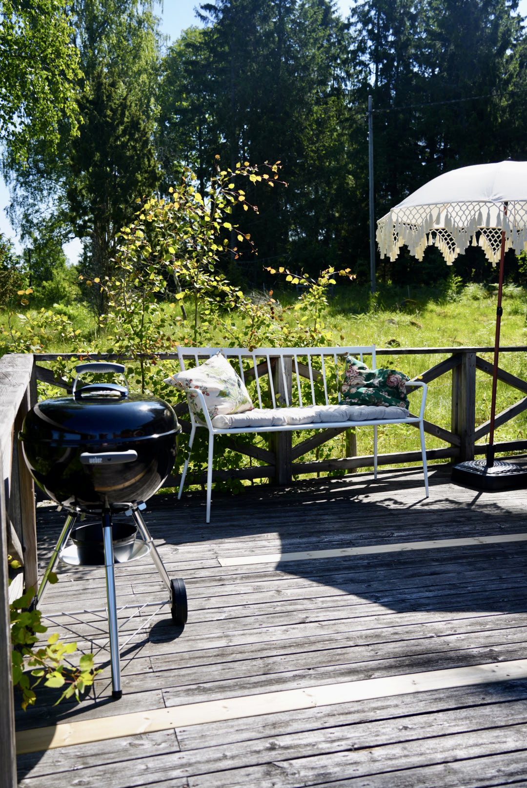 The barbecue and bench on the terrace beside the fringed parasol