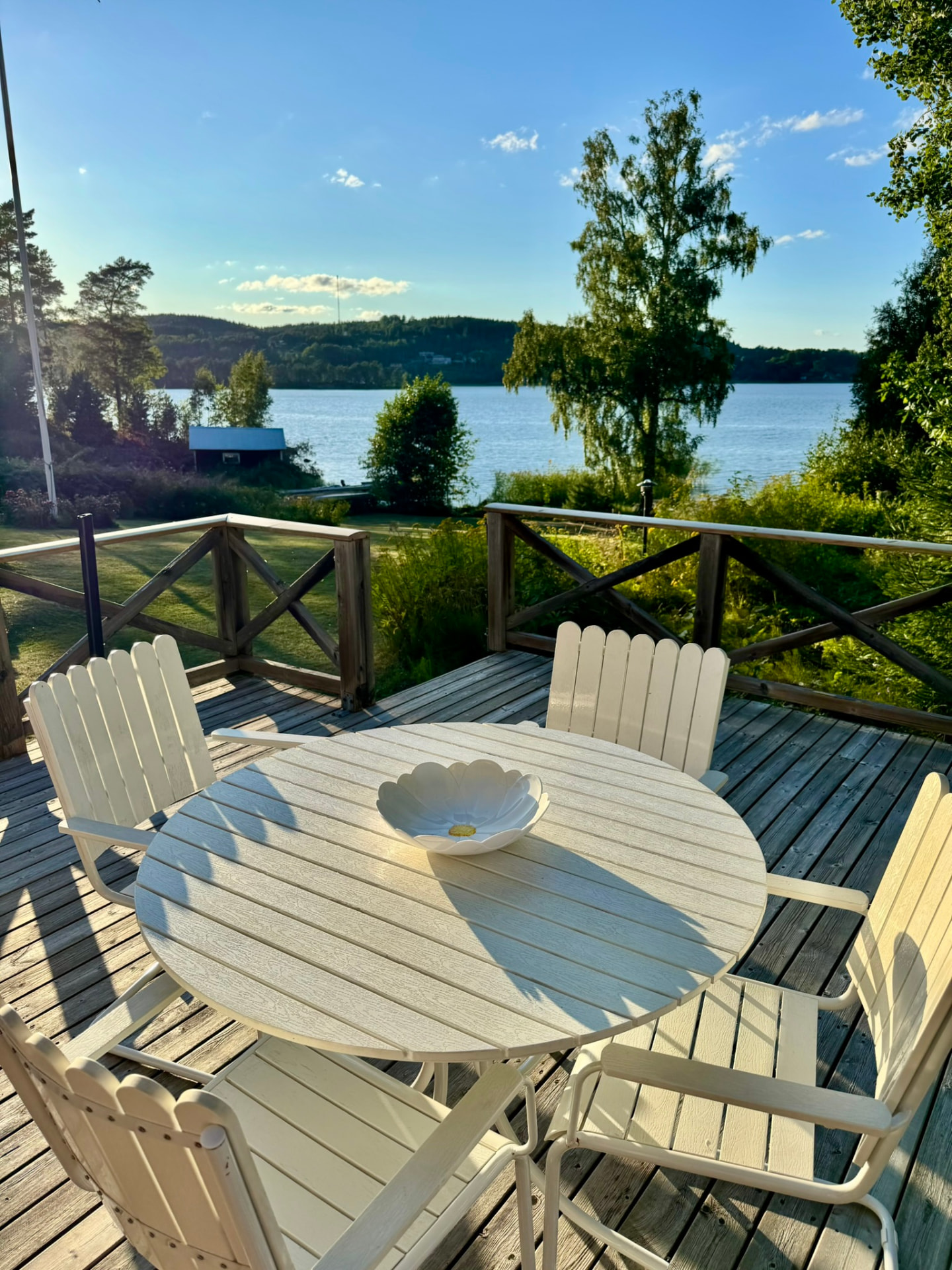 The terrace table and chairs in evening sun with the lake beyond